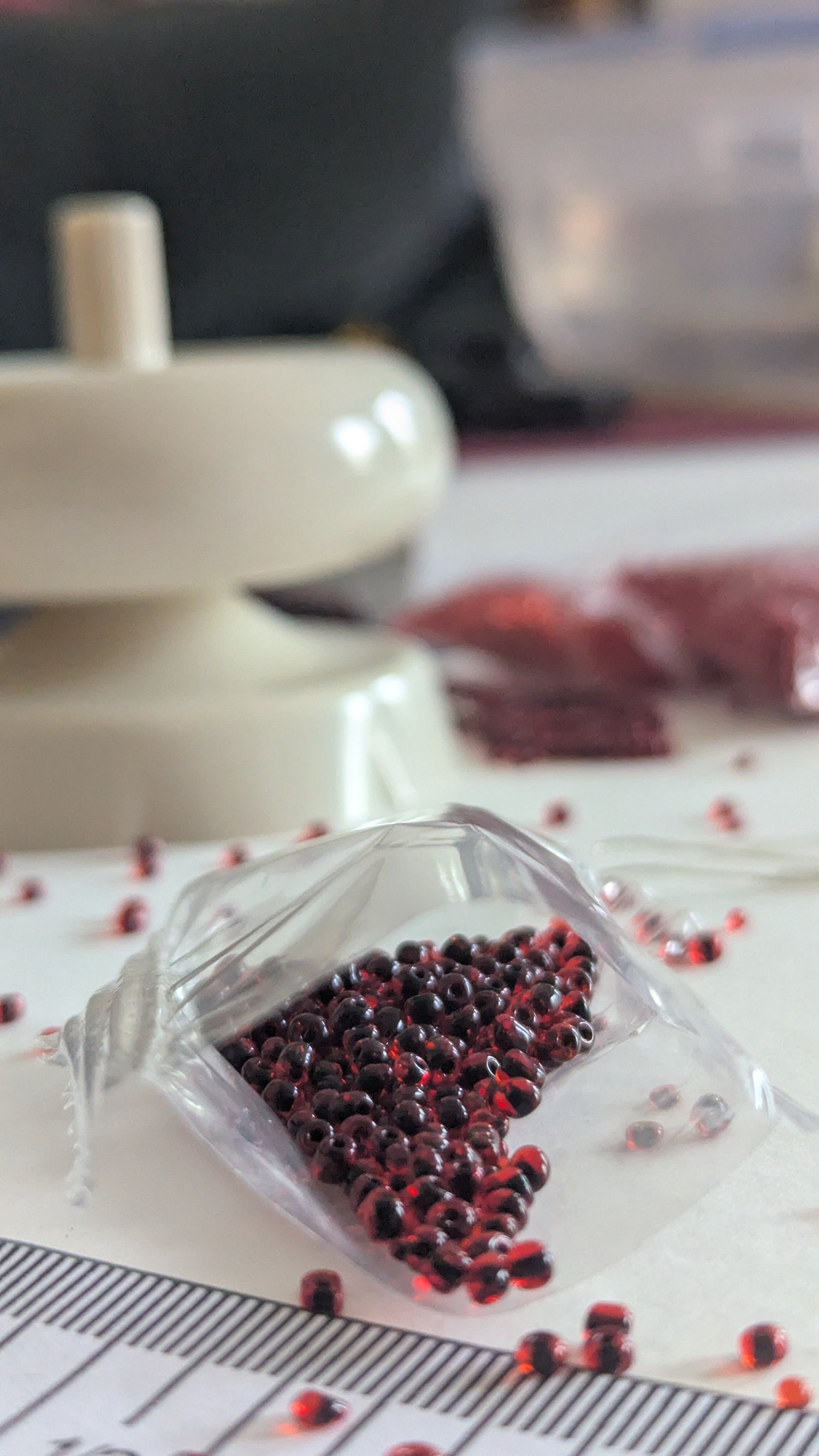 Clear plastic container with red and red seeds on a white surface with measurement markings.