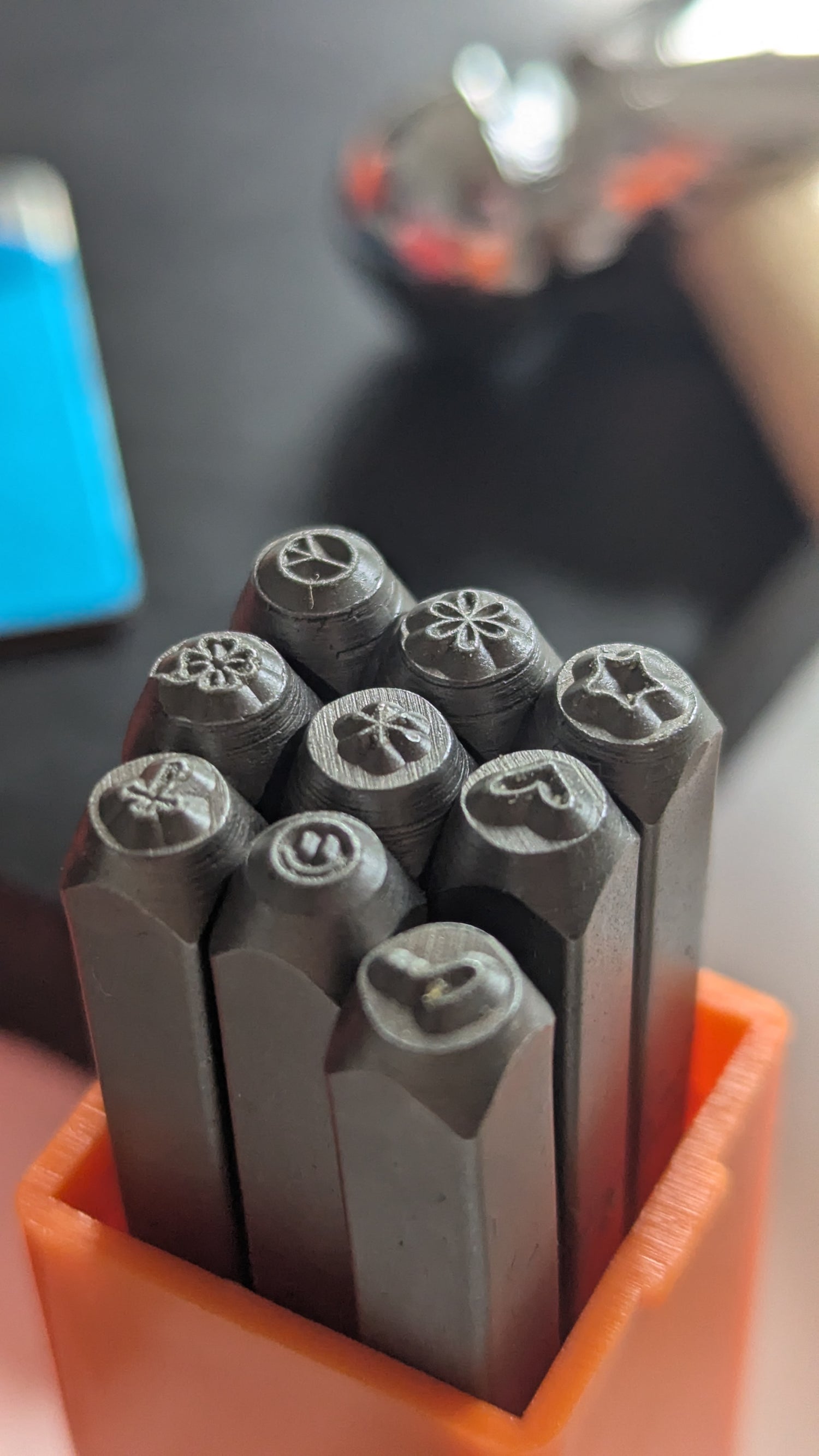 Set of metal stamps in an orange holder with a blurred background